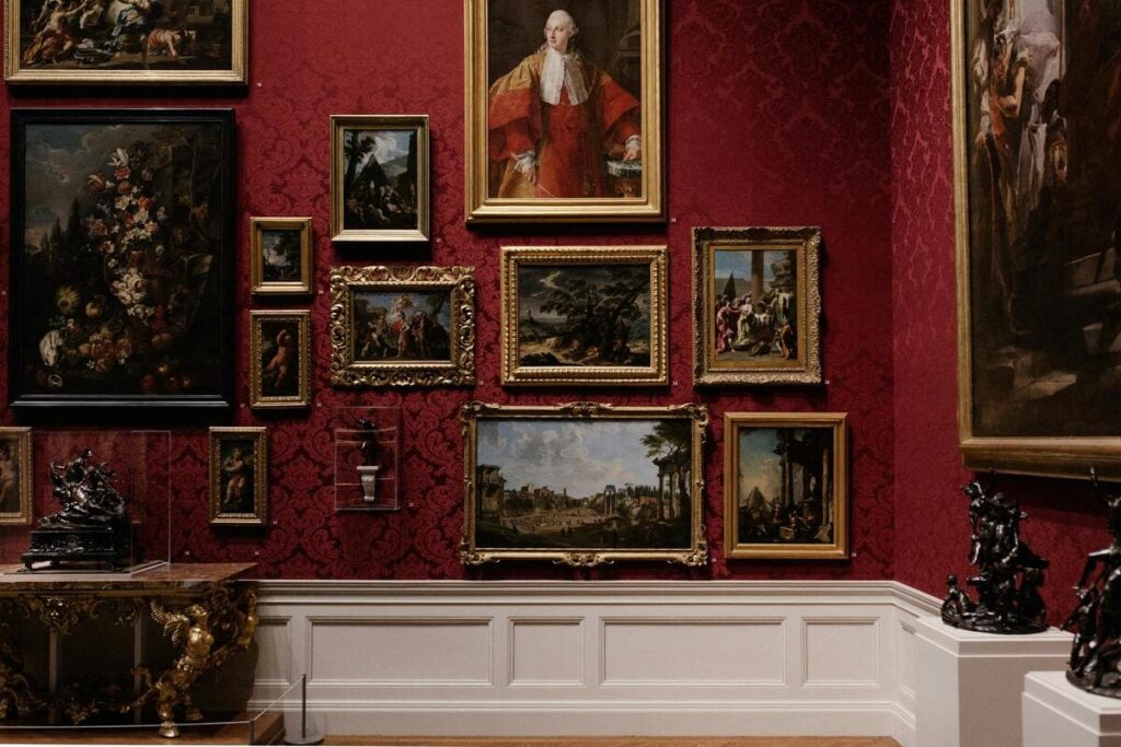 Pared roja decorada con cuadros clásicos enmarcados en oro en una elegante sala.